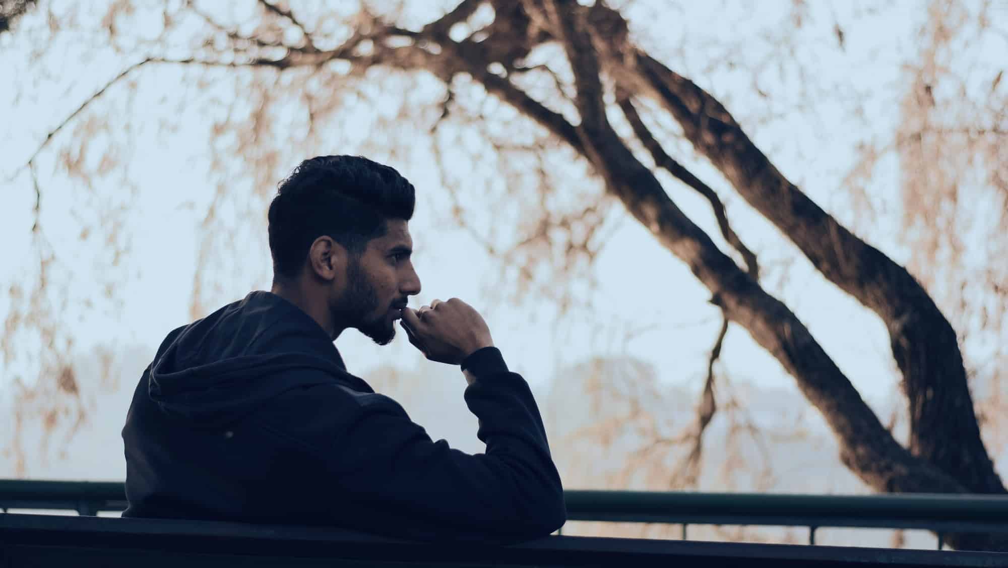 man sitting in front of a tree reflecting after his first year of recovery