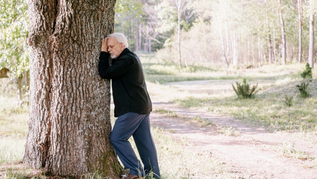 elderly person sitting under a tree practicing healthy coping behavior