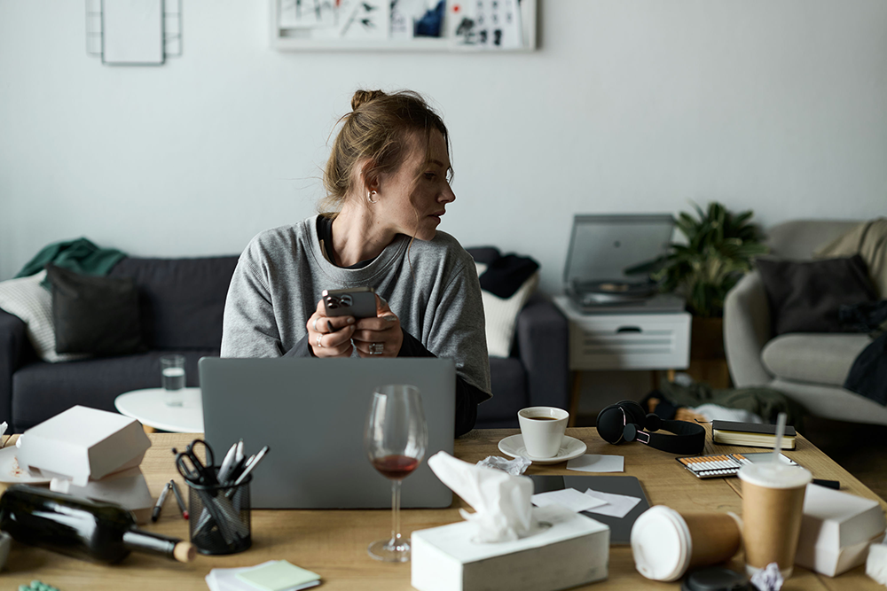 Person with ADHD looking thoughtful at a cluttered desk, representing impulsivity and focus challenges linked to addiction.