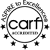 Black and white circular CARF Accredited logo with “Aspire to Excellence” in an arc at the top, five stars at the bottom, and the word “carf” in large lowercase letters in the center.